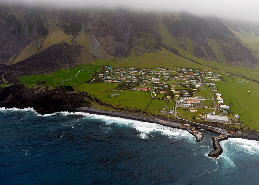 An aerial shot of the island showing the tiny community at the foot of large cliffs